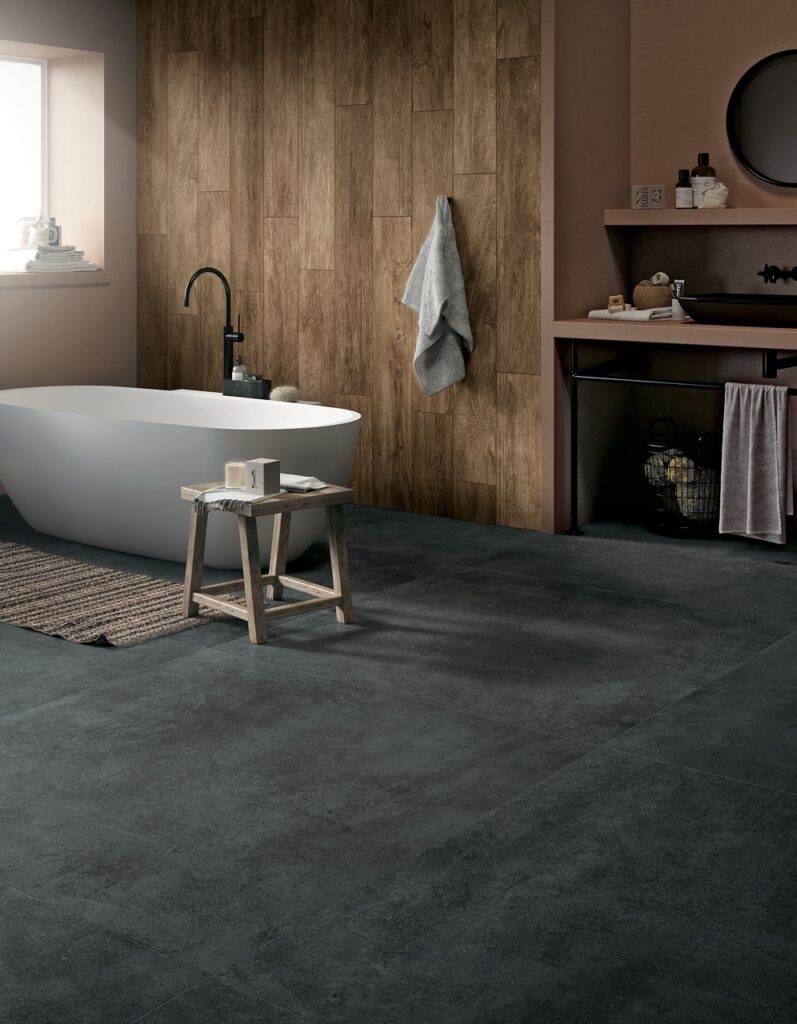 Modernes Bad mit dunklen Großformat-Fliesen, Holzoptik-Wand und freistehender Wanne