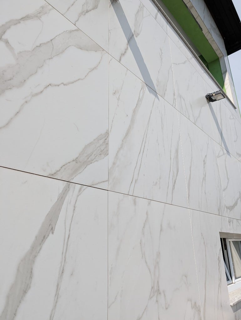 Großformatiges Feinsteinzeug in weißer Marmoroptik an einer Fassade